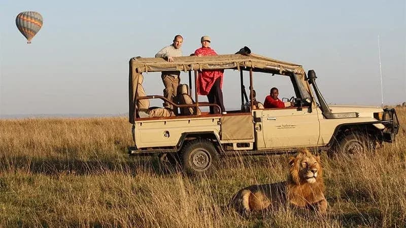Safari vehicle on the Kenyan plains with a balloon in the distance